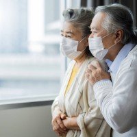 asian-retired-elderly-couple-wearing-face-masks-watch-world-through-their-home-window-hand-hug-lonely-sadness-expressionasian-people-home-isolation-social-distancing-stay-home-ideas-concept